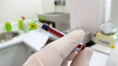 Medical setting: syringe held in a gloved hand
