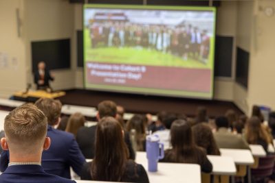 Students sit facing the front of a classroom during Public Presentation Day
