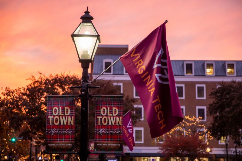 Streetlight at dusk with Virginia Tech flag and Old Town Alexandria banners on it